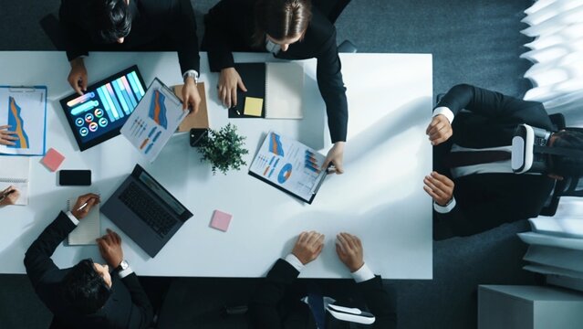 Top down aerial view of smart businessman use vr headset to enter virtual world at meeting while diverse business people send financial information and data analysis graph in database. Directorate.