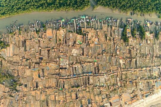 Aerial view of a sprawling settlement where dwellings cluster tightly together, meeting the river's edge in a maze of boats and buildings, Sundarban, Khulna Division, Bangladesh.