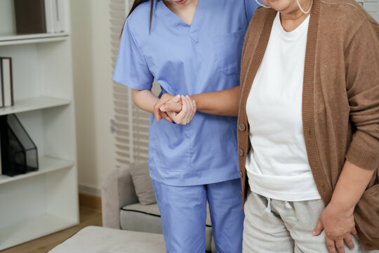 Close up of hand support from female asian physiotherapist during elderly walking practice with senior asian woman for strength recovery and movement improvement therapy - Powered by Adobe