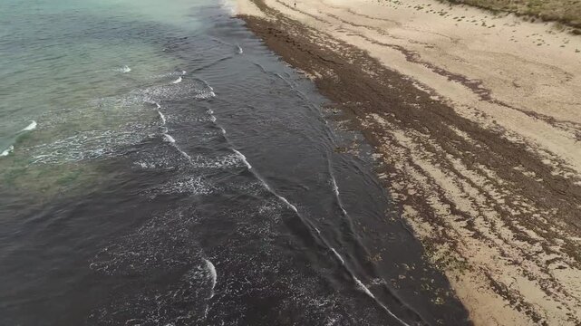 Vid&eacute;o a&eacute;rienne des petites vagues de l'oc&eacute;an Atlantique arrivant sur le rivage. Travelling arri&egrave;re de la plage vers l'oc&eacute;an avec prise d'altitude.