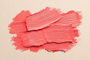 Thick paint strokes in living coral color create an abstract painting on a textured canvas, adding a touch of modern art