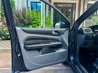 This stylish car door interior features a modern vehicle design accompanied by a beautiful scenic background, offering both aesthetic appeal and comfortable access for all passengers