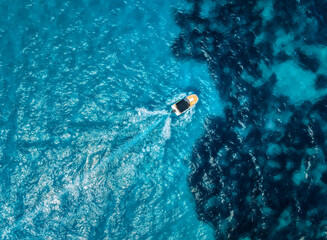 Aerial drone view of small motorboat leaving curved wake in deep blue and turquoise Mediterranean sea, dynamic summer scene near Mallorca, Balearic Islands, Spain, top view, clear water, sunny day