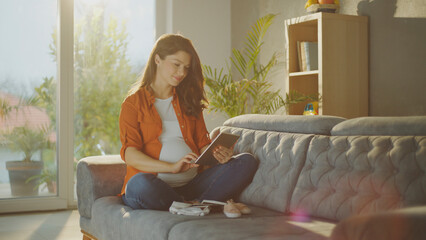 Pregnant woman using tablet and shopping online for baby clothes