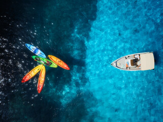 Aerial drone top view of colorful kayaks and motorboat on crystal clear turquoise water. Summer adventure and recreation in Mallorca, Balearic Islands, Spain. Mediterranean sea, coastline. Top view