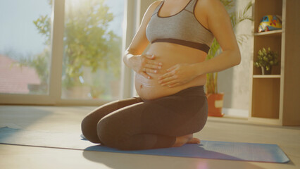 Pregnant woman applying cream on her belly at home