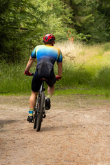 Naklejka premium Cycling fast through the woods, a mountain biker steps on the pedals and rides through the woods during a race
