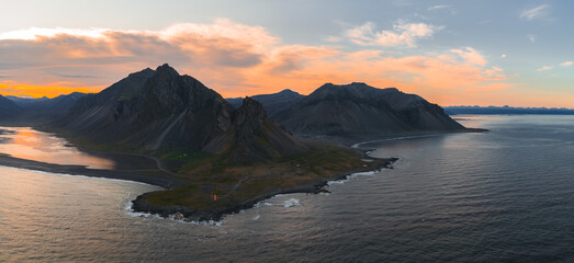Aerial view of Iceland's Stokknes Peninsula with Vestrahorn's jagged peaks, a black sand beach,...