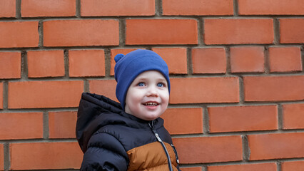 Portrait of a happy blue-eyed child against a brick wall.