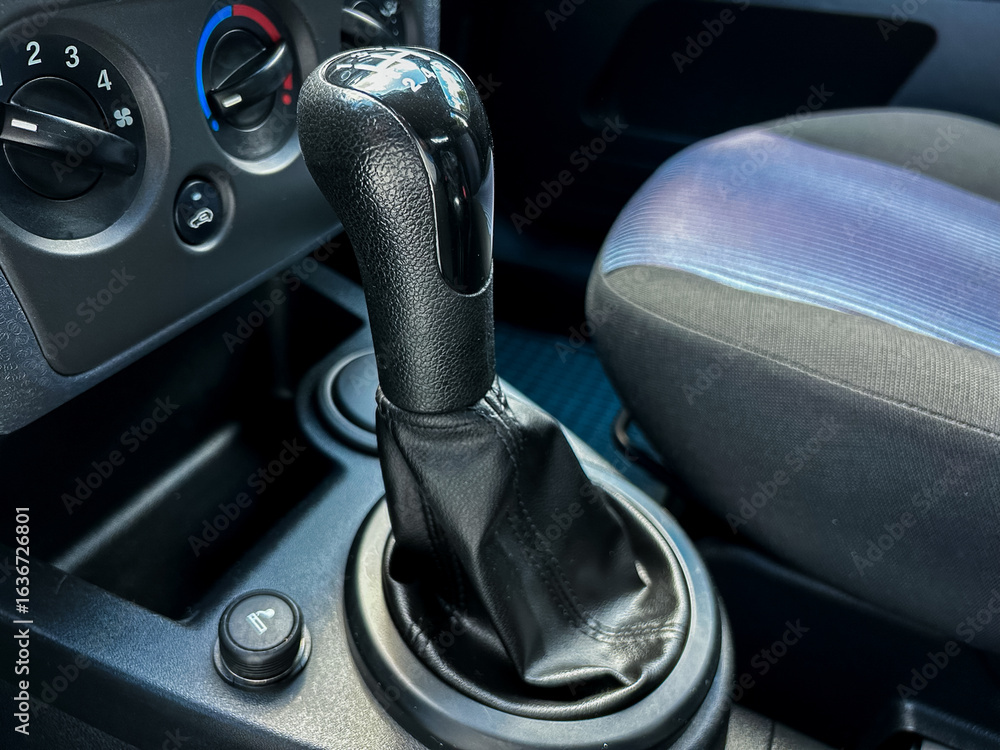 Poster this image showcases the interior of a car, highlighting a manual gear shift handle along with the c