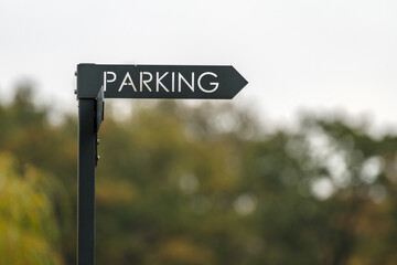 drogowskaz z napisem parking na rozmytym tle