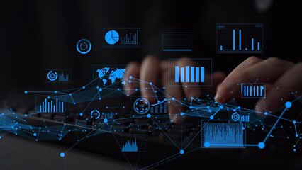 A person types on a keyboard enveloped by blue-colored data visualization graphics and analytics charts, representing modern technology and data analysis in a professional workspace. Xenic