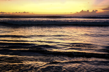 Beautiful and exotic sunset at Kuta Beach, Bali, Indonesia, captured from the shoreline. The golden sky reflects on the waves, attracting many tourists to witness this must-see view in Bali.