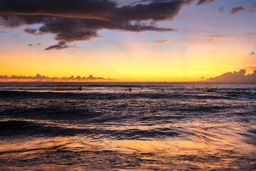 Fototapeta premium Beautiful and exotic sunset at Kuta Beach, Bali, Indonesia, captured from the shoreline. The golden sky reflects on the waves, attracting many tourists to witness this must-see view in Bali.