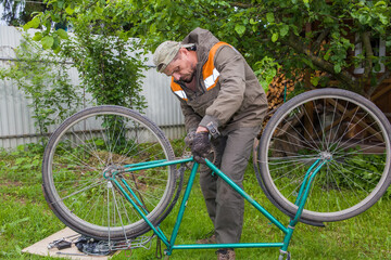 A man, European, 50 years old, repairing an old bicycle.