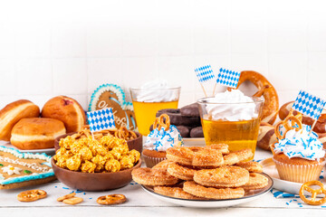 Oktoberfest festive food, with various snacks, sweets, desserts, pretzels, beer jelly, gingerbread cookies hearts, salted crackers, popcorn, jam donuts, cupcakes. Oktoberfest brunch menu background