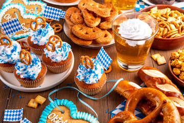 Oktoberfest festive food, with various snacks, sweets, desserts, pretzels, beer jelly, gingerbread cookies hearts, salted crackers, popcorn, jam donuts, cupcakes. Oktoberfest brunch menu background
