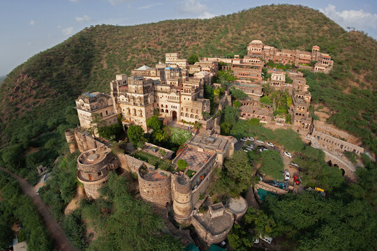Aerial view of the majestic Taragarh Fort complex, a historic marvel perched atop a hill amid verdant foliage, Bundi, Rajasthan, India.