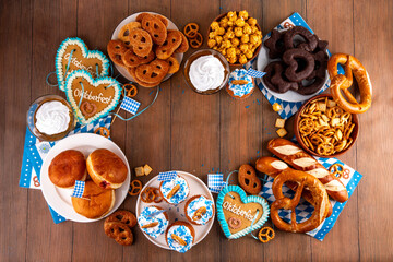 Oktoberfest festive food, with various snacks, sweets, desserts, pretzels, beer jelly, gingerbread cookies hearts, salted crackers, popcorn, jam donuts, cupcakes. Oktoberfest brunch menu background