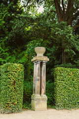 Amidst the vibrant and lush greenery of a serene garden, an Ancient Stone Pillar proudly stands,...
