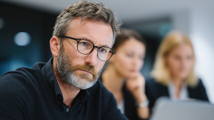A focused business leader, radiating intelligence and determination, engages in a productive meeting, his intense gaze reflecting deep thought and strategic planning within a modern office setting.