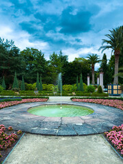 A tranquil and peaceful garden features a stunning central fountain, beautifully surrounded by an...