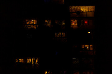 A tall building featuring numerous windows that are illuminated against the backdrop of the night...