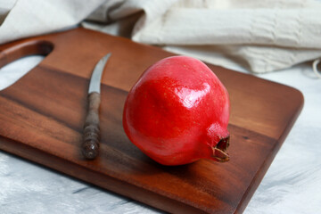 Fresh red pomegranate fruit on wooden cutting board.