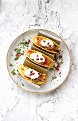 Mexican tacos with fresh vegetables and salsa on a white plate and white background