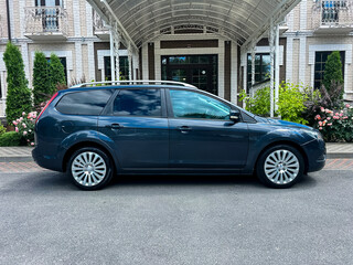 A fashionable and stylish dark grey family vehicle is parked in a beautifully elegant setting that features lush landscaping, creating a picturesque atmosphere that enhances its appearance and appeal