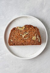 Homemade banana bread with carrot and walnuts on a white plate and white background