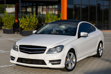 A sleek white luxury coupe positioned in an urban setting, perfectly showcasing its modern design, sophisticated aesthetics, and impressive performance capabilities that set it apart from others