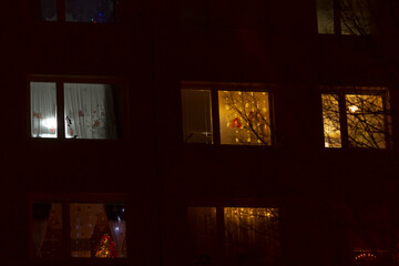 As night falls, the windows of a building begin to glow, illuminating the dark surroundings with...