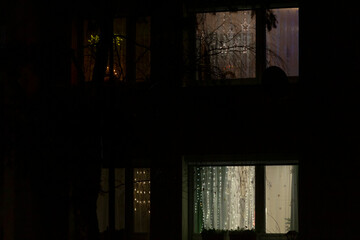 A person is gazing thoughtfully out of a window into the dark night sky as the moonlight casts...
