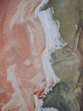 Aerial view of a striking contrast between the pink salt ponds and the adjacent land, separated by a vibrant white strip, Aigues-Mortes, Occitanie, France.