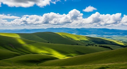 Obraz premium Rolling green hills under a bright blue sky with fluffy white clouds create a peaceful and scenic landscape