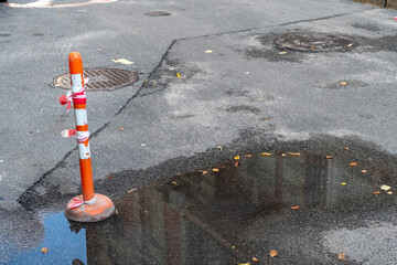 Traffic cone with warning tape on wet asphalt road construction safety barrier urban infrastructure...