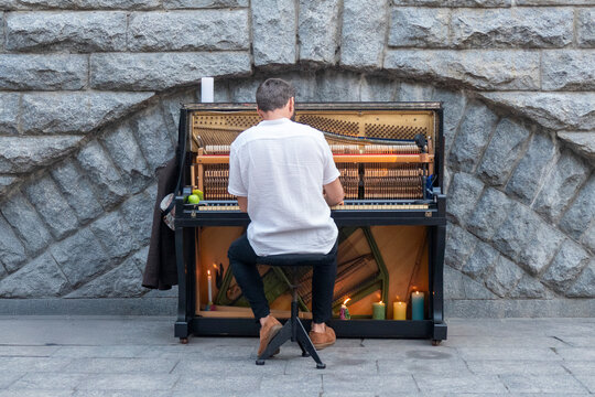 Street Musician Playing Public Piano Against Stone Wall - Urban Music and Street Performance Art