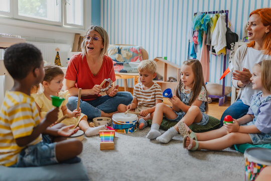 Diverse group of preschool children and teachers playing musical instruments in a colorful kindergarten classroom, engaging in fun early education and creative learning activities