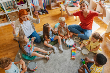 Diverse group of preschool children and teachers playing musical instruments in a colorful...
