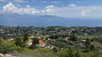 Stunning coastal village nestled along Greece azure waters showcases vibrant homes, lush greenery,...