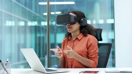 Successful young african american businesswoman using VR glasses for video call and online chat in virtual reality simulator sitting at workplace in modern business office. Remote online conference - Powered by Adobe