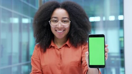 Happy african american businesswoman showing mobile phone with green screen in business office. Color key, vertical template layout for advertising. Woman looking at camera holding smartphone Close up - Powered by Adobe