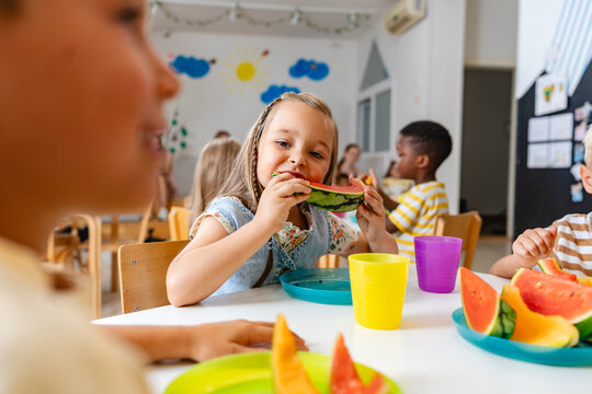 Preschool children enjoying fresh watermelon slices during snack time in bright and cheerful classroom
