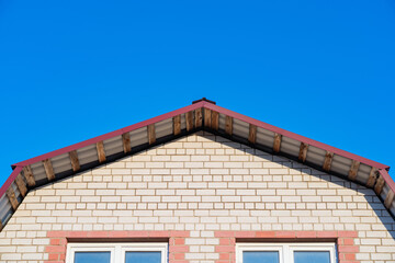 the wall of a brick house with a roof made of profile iron and skylights, construction industry