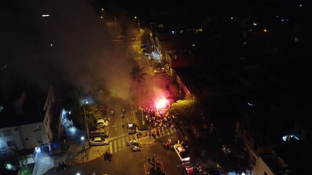 Smoke and flares fill a city street at night, creating a dramatic scene of urban unrest