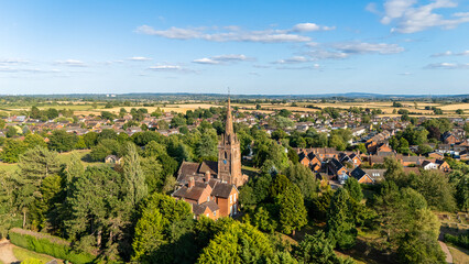 Local Church in the centre of a rural village surrounded by houses, Aerial view of trees and houses in a countryside setting