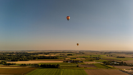 Heißluftballons gleiten über ein weites, ländliches Panorama bei Sonnenuntergang