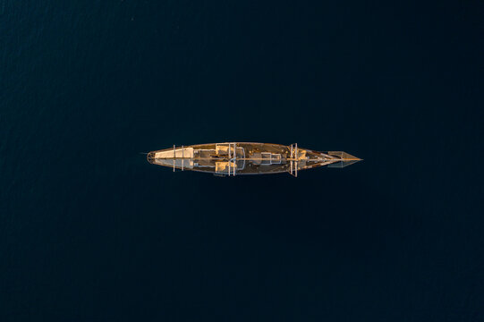 Aerial view of a ship sitting silently on the dark blue water, the vessel's weathered surface contrasting with the surrounding serene sea, Ermioni, Argolis, Greece.