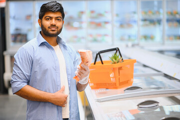 Indian man choosing fresh fish in supermarket freezer section